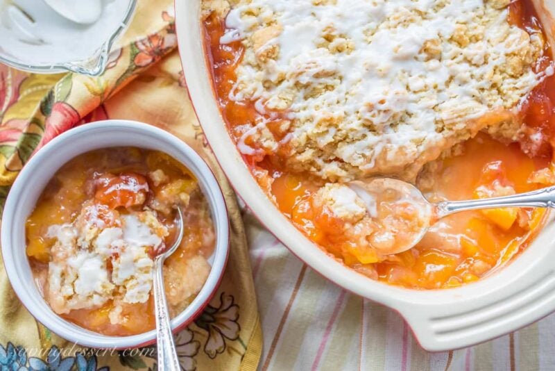 A casserole dish with a peach crumble topped with a drizzled icing