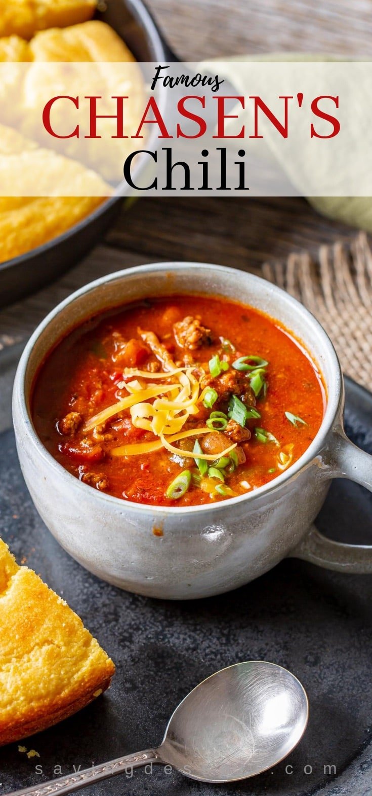 A cup of beefy Chasen's Chili topped with grated cheese and sliced green onions.