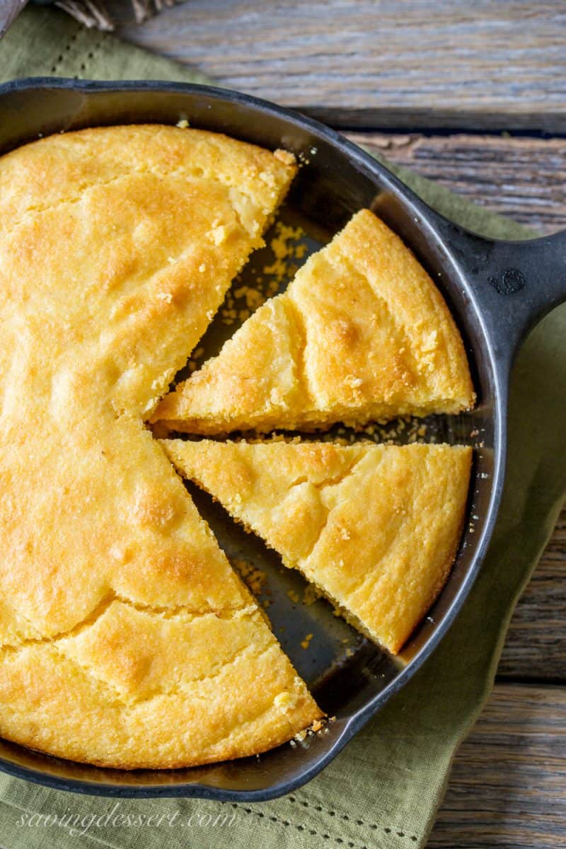 A cast iron skillet with a cake of sliced cornbread