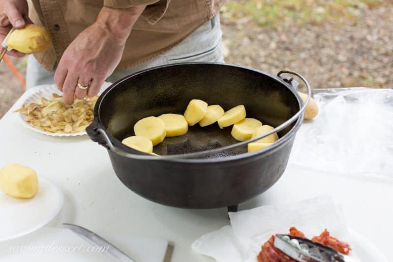 A camping cast iron pot filled with sliced potatoes