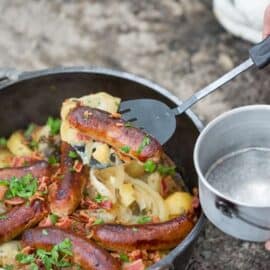 A Dutch oven filled with potatoes, onions and sausages