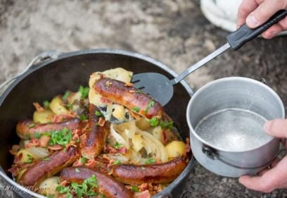 A Dutch oven filled with potatoes, onions and sausages