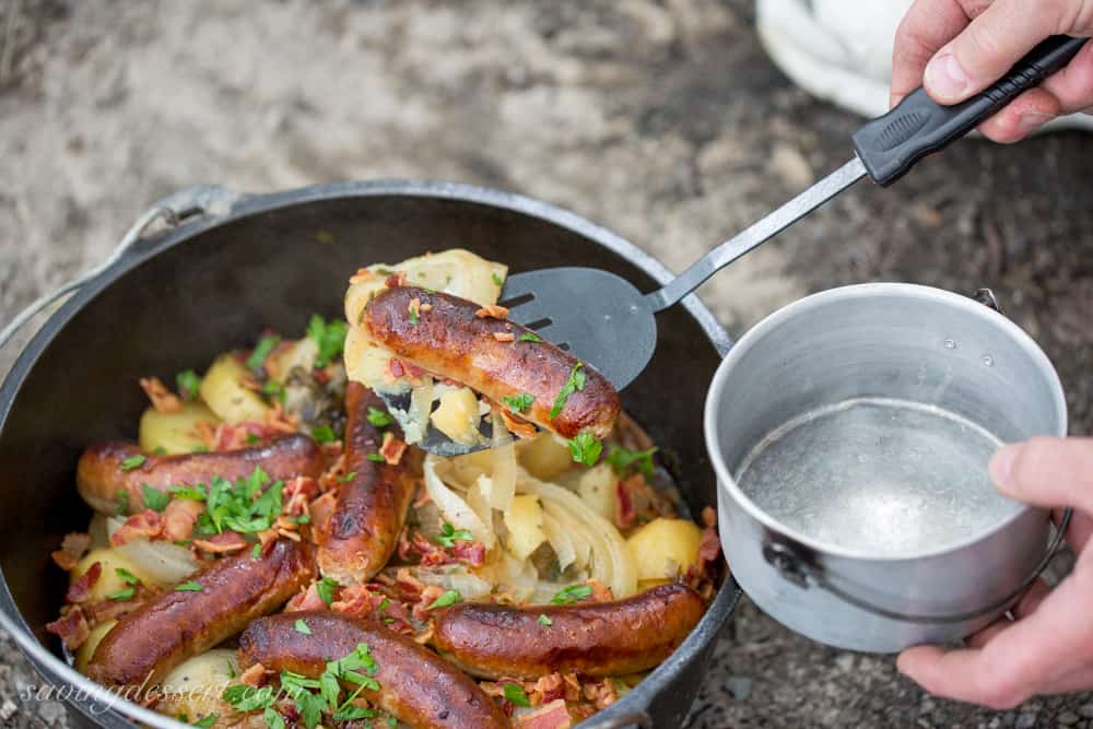 A Dutch oven filled with potatoes, onions and sausages