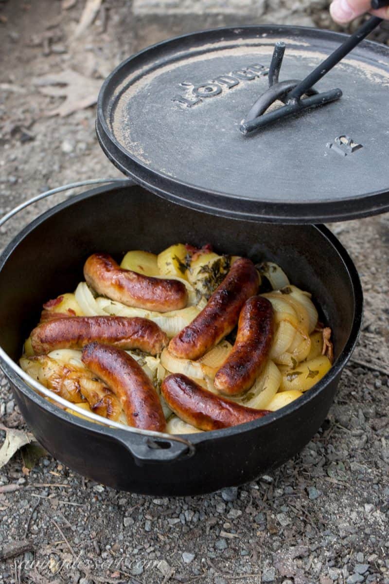 A Lodge Dutch oven filled with sausages, bacon, potatoes and onions
