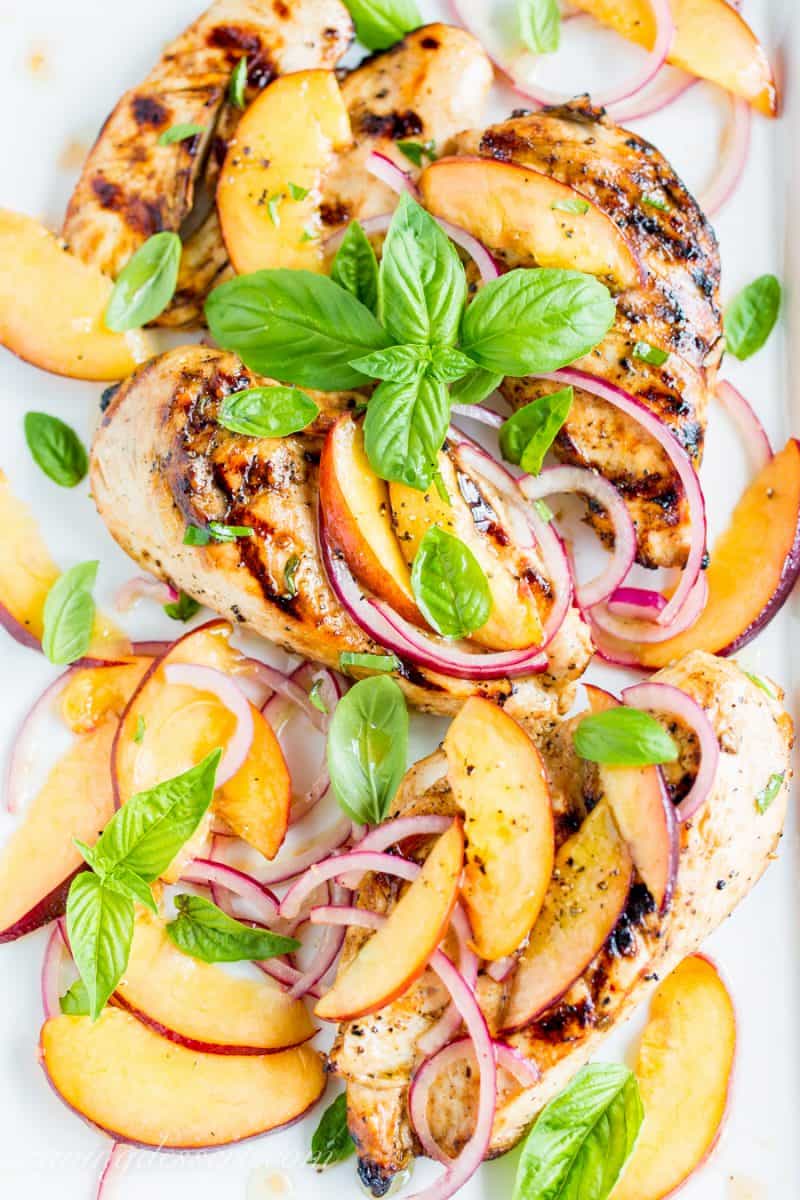 Grilled Chicken on a platter with Nectarine relish and onions garnished with basil leaves