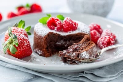 Chocolate lava cake topped with raspberries and served with strawberries.