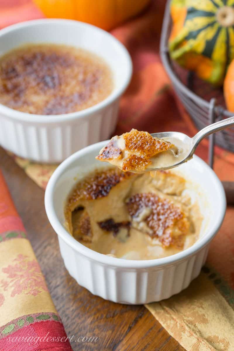Two cups of pumpkin creme brûlée with a cracked burnt sugary top