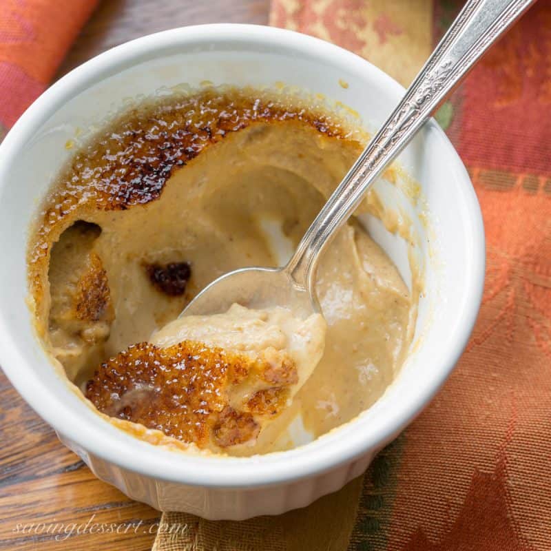 Overhead view of a bowl of pumpkin custard with a cracked hard sugar top with a spoon