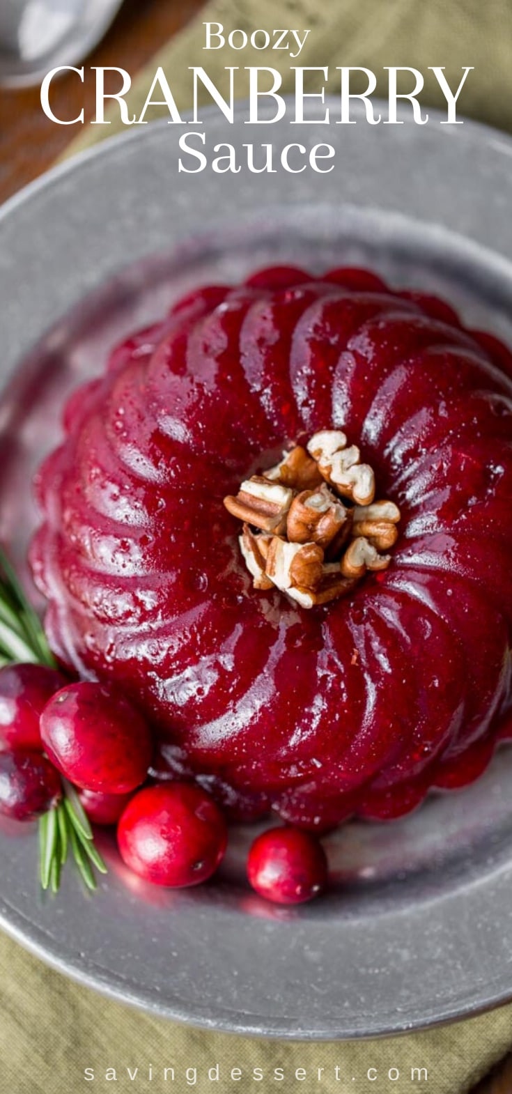 A molded ring of boozy cranberry sauce with fresh cranberry garnish and pecans.