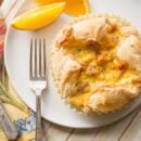 An overhead view of a plate with a flaky breakfast soufflé and a slice of orange