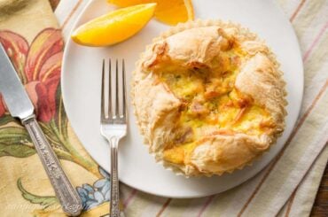 An overhead view of a plate with a flaky breakfast soufflé and a slice of orange