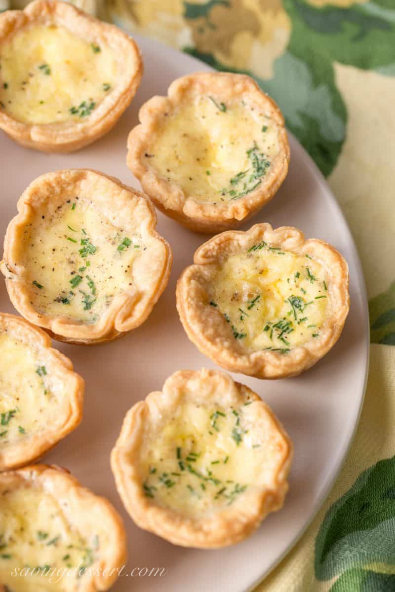 a plate of mini quiche topped with minced chives