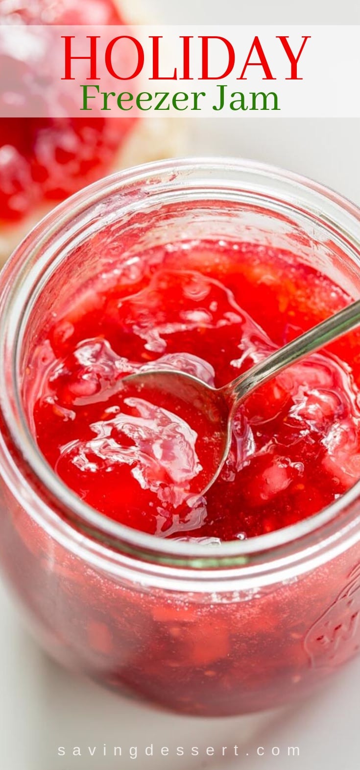An open jar of bright pink Holiday Freezer Jam with a spoon