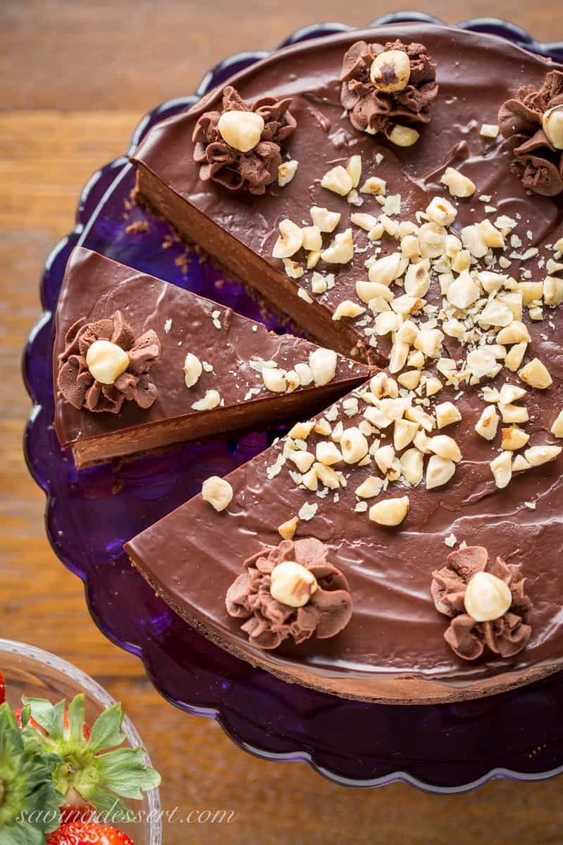 An overhead view of a Chocolate Hazelnut Mousse Cake topped with hazelnuts and chocolate ganache