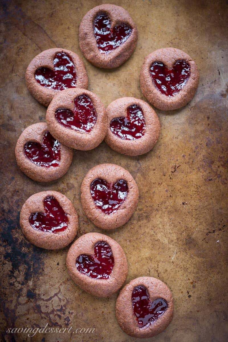 Chocolate Raspberry Thumbprint Cookies - who can resist the classic combination of raspberries and chocolate?! This little chocolate cookie boasts plenty of chocolate flavor and a fun little heart shaped thumbprint filled with seedless raspberry jam. An easy and delicious cookie with a Valentine's Day theme for your sweetie! www.savingdessert.com