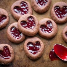 Chocolate Raspberry Thumbprint Cookies - who can resist the classic combination of raspberries and chocolate?! This little chocolate cookie boasts plenty of chocolate flavor and a fun little heart shaped thumbprint filled with seedless raspberry jam. An easy and delicious cookie with a Valentine's Day theme for your sweetie! www.savingdessert.com
