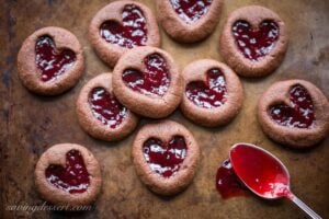 Chocolate Raspberry Thumbprint Cookies - who can resist the classic combination of raspberries and chocolate?! This little chocolate cookie boasts plenty of chocolate flavor and a fun little heart shaped thumbprint filled with seedless raspberry jam. An easy and delicious cookie with a Valentine's Day theme for your sweetie! www.savingdessert.com