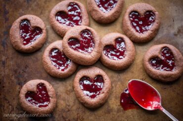 Chocolate Raspberry Thumbprint Cookies - who can resist the classic combination of raspberries and chocolate?! This little chocolate cookie boasts plenty of chocolate flavor and a fun little heart shaped thumbprint filled with seedless raspberry jam. An easy and delicious cookie with a Valentine's Day theme for your sweetie! www.savingdessert.com