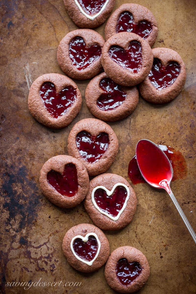 Chocolate Raspberry Thumbprint Cookies - who can resist the classic combination of raspberries and chocolate?! This little chocolate cookie boasts plenty of chocolate flavor and a fun little heart shaped thumbprint filled with seedless raspberry jam. An easy and delicious cookie with a Valentine's Day theme for your sweetie! www.savingdessert.com