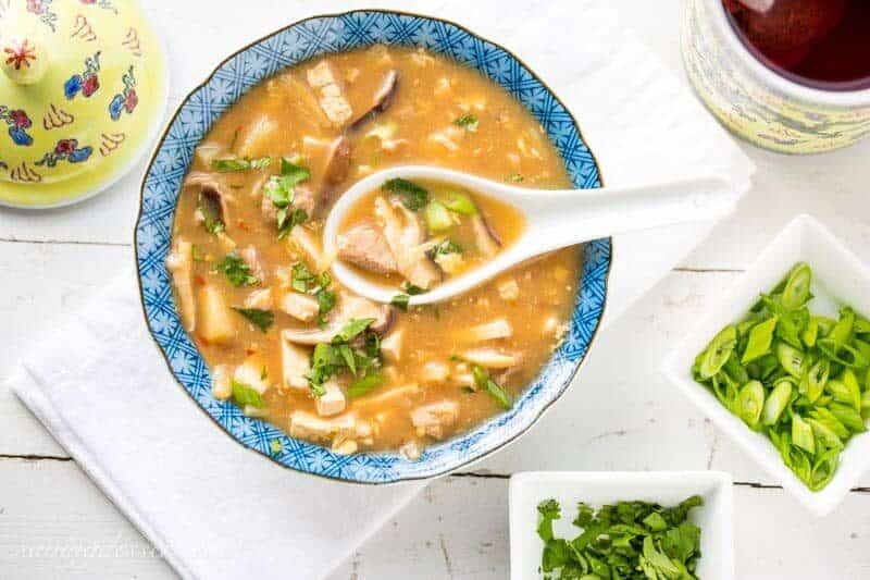 A bowl of Hot and Sour Soup garnished with green onions and cilantro