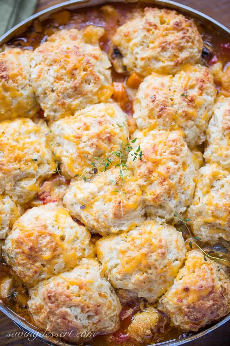 A skillet filled with vegetables topped with cheesy biscuits