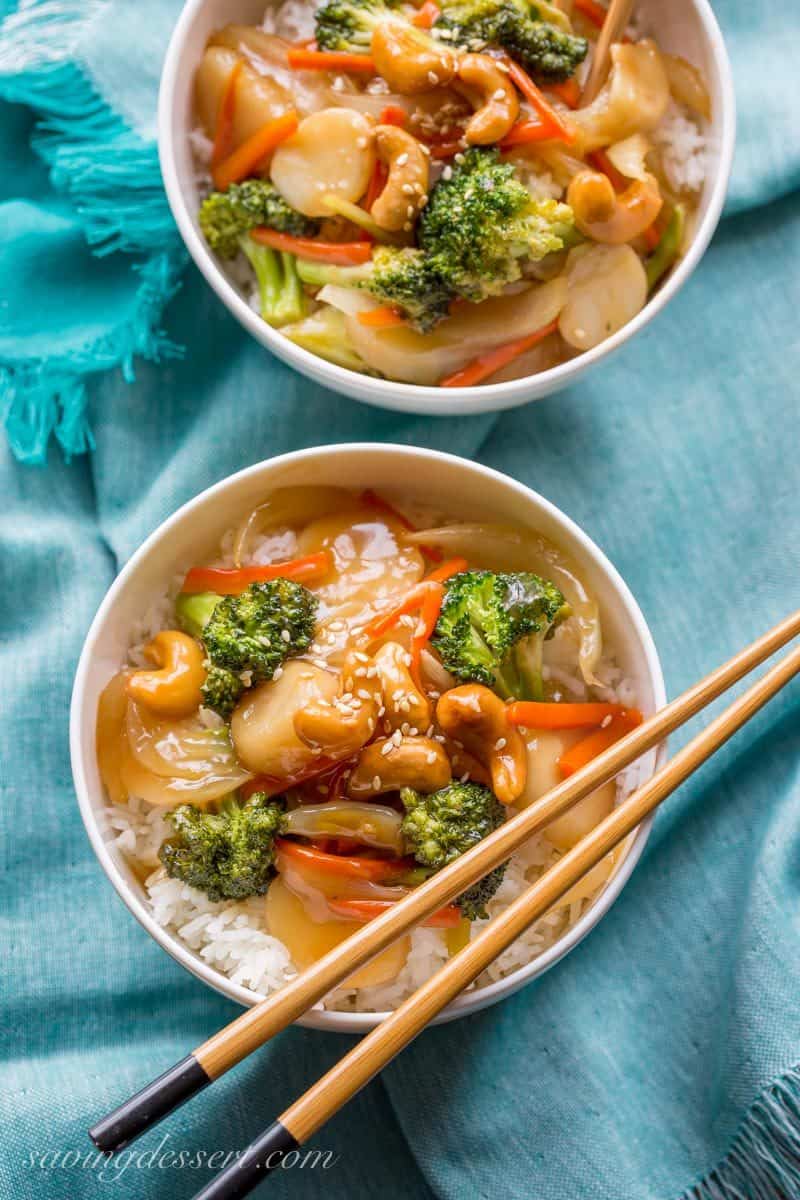 Bowls of rice topped with vegetables, cashews and sesame seeds