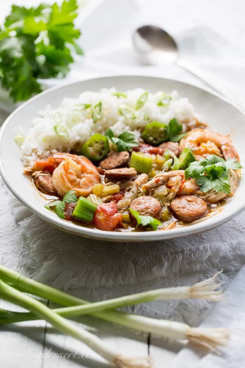 A bowl of Cajun gumbo with sausage shrimp and chicken served with rice and sliced green onions