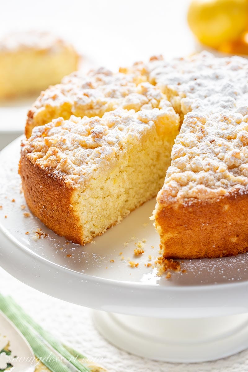 A sliced lemon cake with a crumble topping on a cake stand