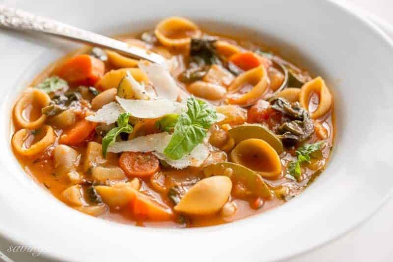 A bowl of Winter Minestrone soup with pasta, fresh grated Parmesan, vegetables and beans