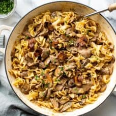 Overhead view of a casserole pan filled with sliced beef, egg noodles, mushrooms in a rich gravy