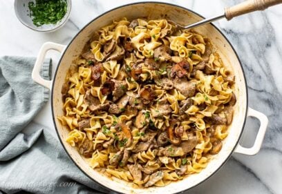 Overhead view of a casserole pan filled with sliced beef, egg noodles, mushrooms in a rich gravy