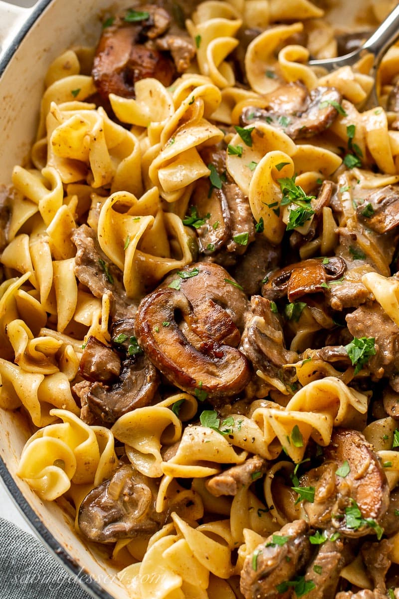 A closeup of Beef Stroganoff in a skillet with egg noodles and mushrooms