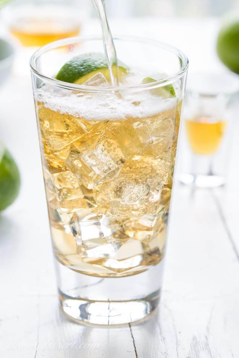 A glass of Jameson Irish Whiskey poured over ice with ginger ale and lime wedges