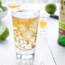 A glass of Jameson and ginger ale on a table with limes.