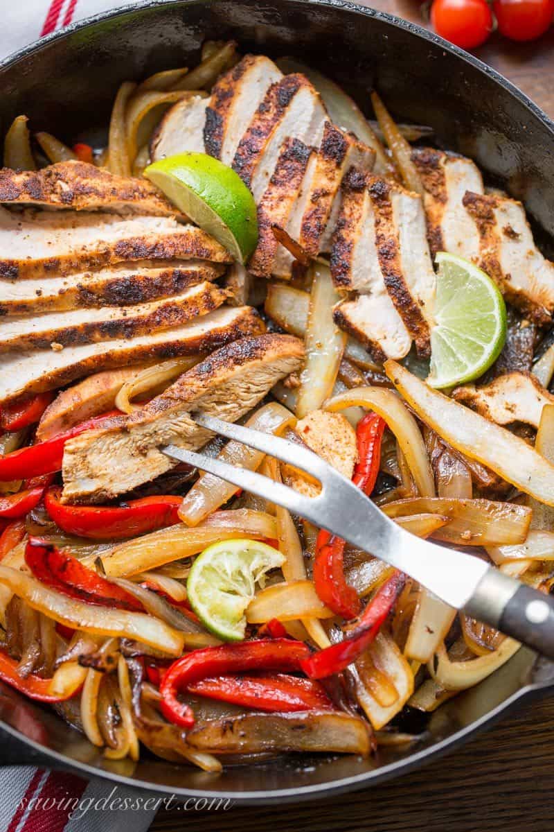 Chicken fajitas with peppers, onions and lime in a cast iron skillet