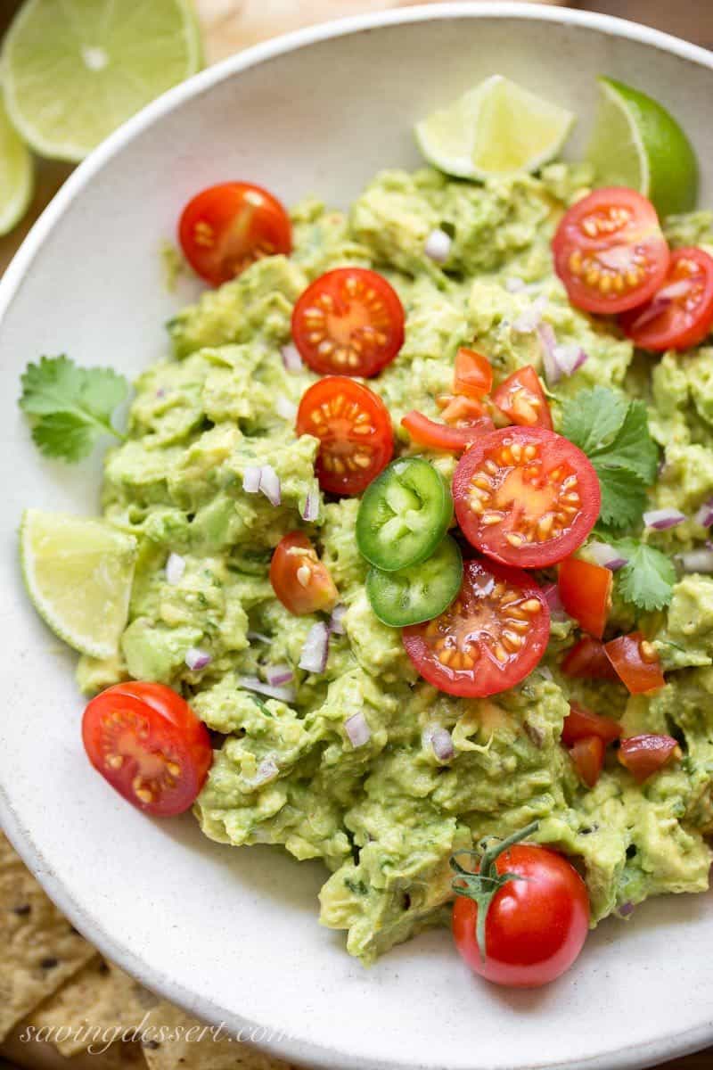 a bowl of spicy guacamole with tomatoes and jalapeños