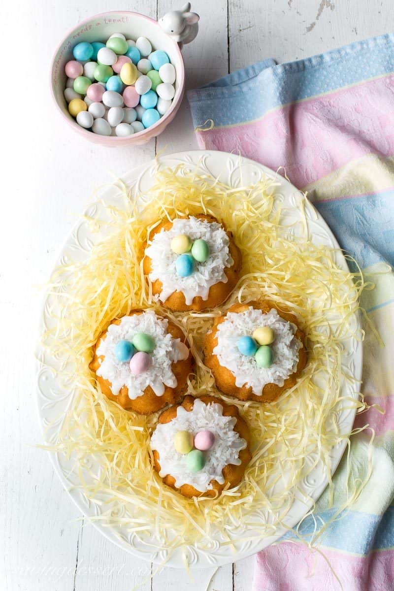Mini Coconut Pound Cakes all dressed up for Easter fun! Baked in a mini bundt pan, topped with a simple coconut flavored icing and garnished with shredded coconut and pastel colored candy eggs. www.savingdessert.com