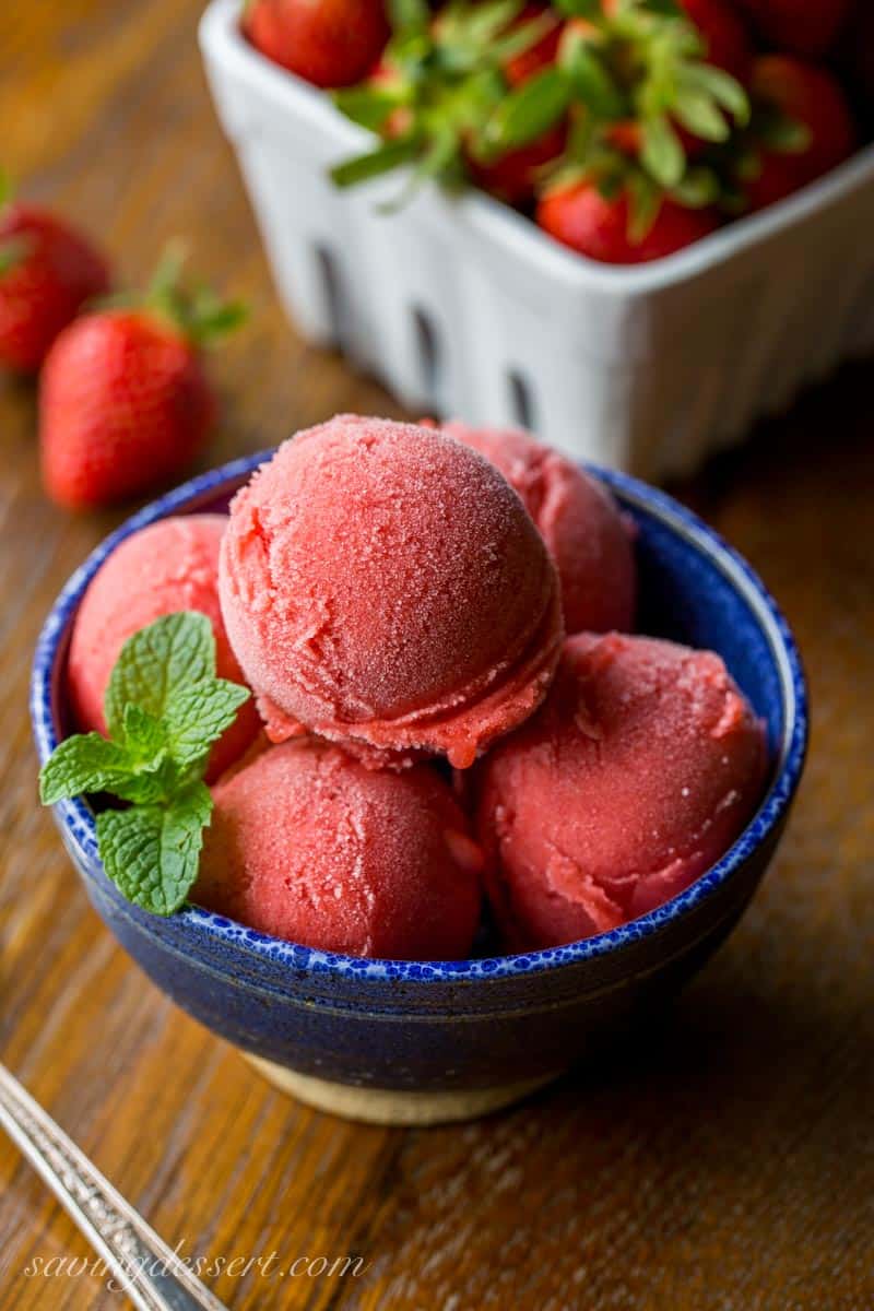 A bowl with scoops of strawberry sorbet garnished with mint leaves