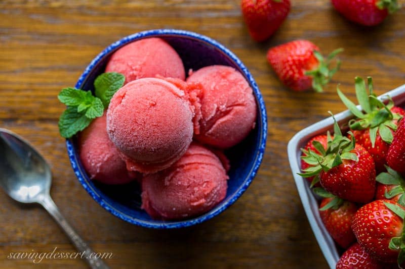 An overhead photo of a bowl of strawberry sorbet with fresh strawberries on the side.