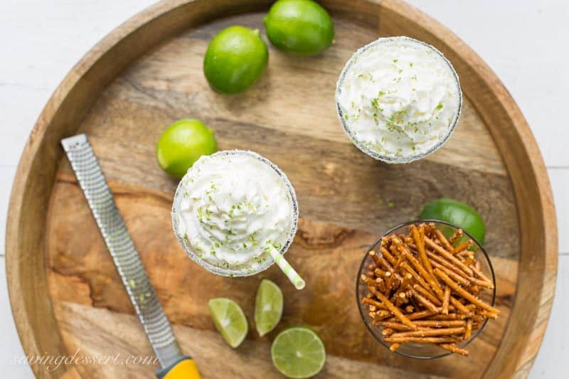 An overhead view of two glasses filled with a lime Margarita milkshake with pretzels on the side