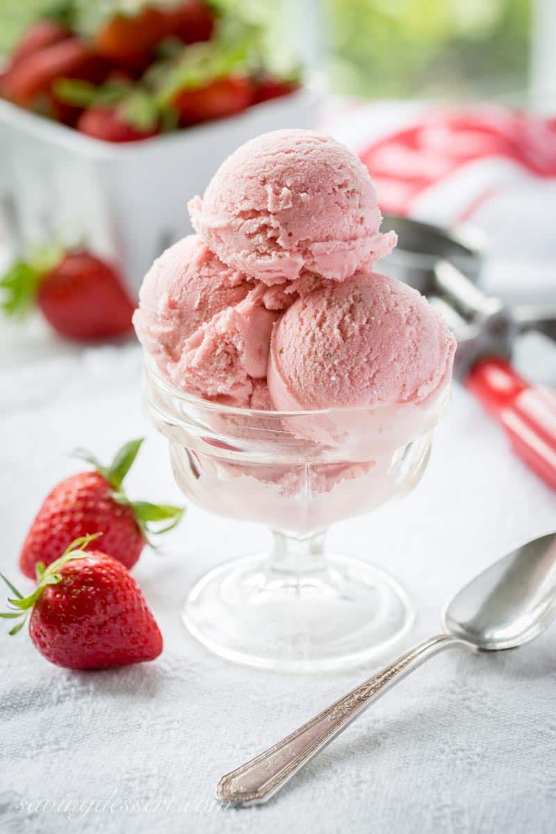 A small bowl of strawberry ice cream served with fresh strawberries.