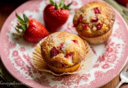 Strawberry muffins on a plate with fresh strawberries on the side