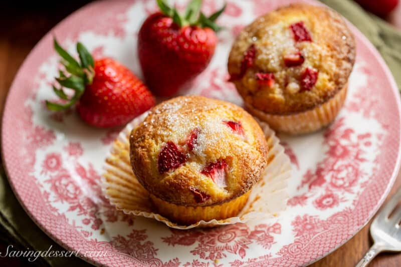 Strawberry muffins on a plate with fresh strawberries on the side