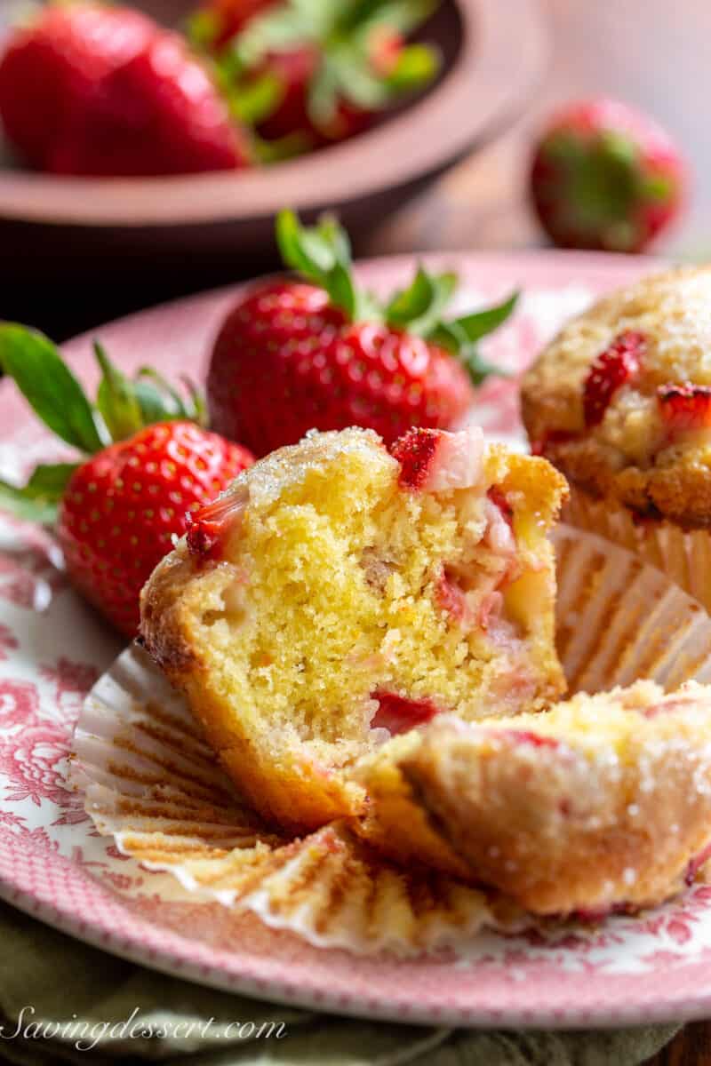 a strawberry muffin on a plate cut in half showing a fluffy interior