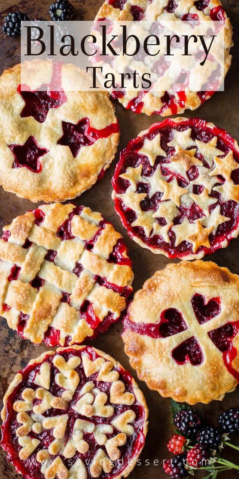 Overhead view of a baking tray filled with beautiful little blackberry tarts with double crusts