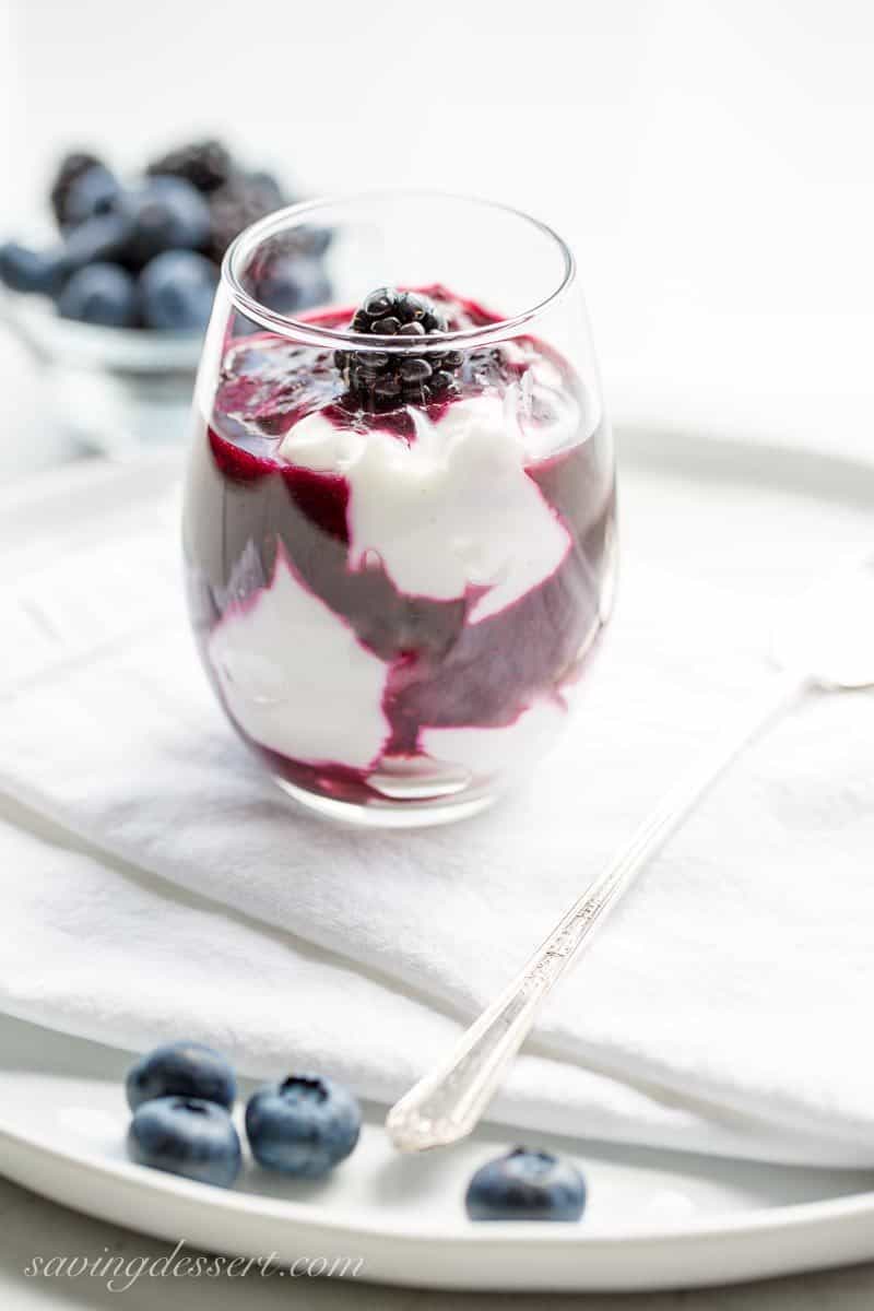 A glass with yogurt and warm black and blueberry sauce