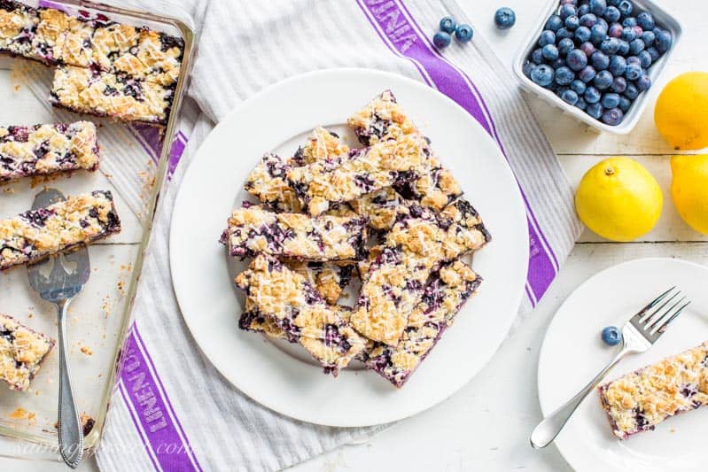An overhead view of a plate of blueberry bars with lemons on the side