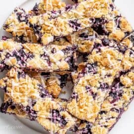 A plate of blueberry crumb bars topped with lemon icing