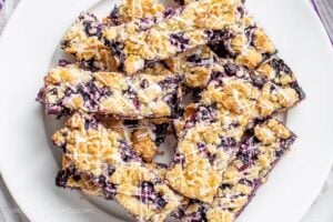 A plate of blueberry crumb bars topped with lemon icing