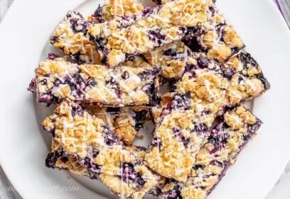 A plate of blueberry crumb bars topped with lemon icing